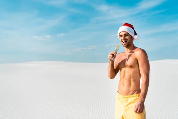 Homme sexy dans santa chapeau tenant verre de champagne sur la plage aux Maldives — Photo de stock