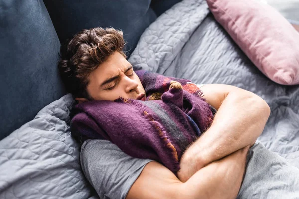 Homme malade et beau dans l'écharpe avec les yeux fermés couché dans le lit — Photo de stock