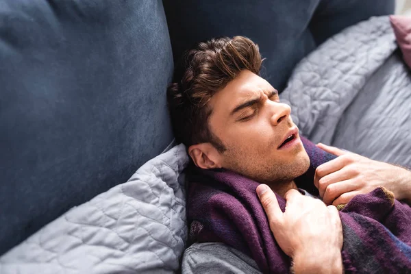 Homme malade et beau dans l'écharpe avec les yeux fermés couché dans le lit — Photo de stock