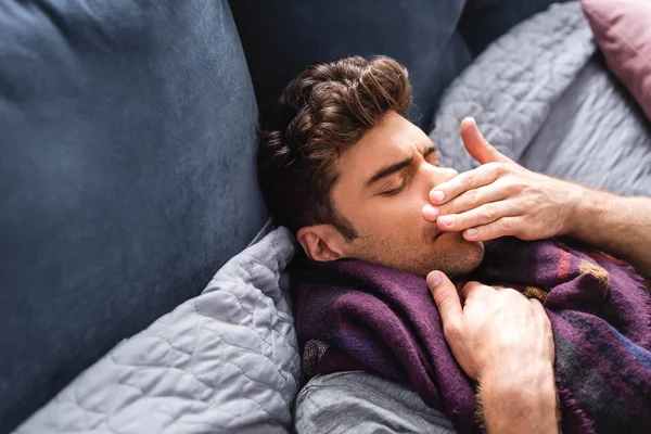 Homme malade et beau dans l'écharpe avec les yeux fermés couché dans le lit — Photo de stock