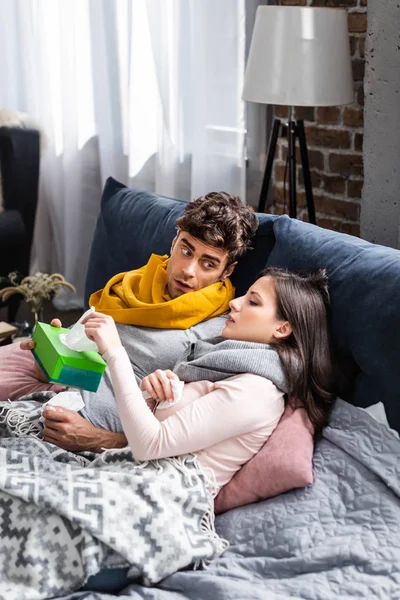 Sick girlfriend taking napkin and boyfriend holding box in apartment — Stock Photo