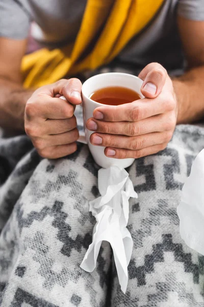 Vista cortada do homem segurando xícara de chá no apartamento — Fotografia de Stock