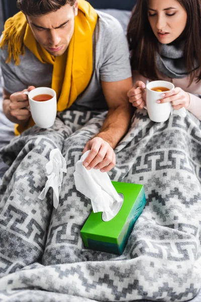High angle view of sick girlfriend holding cup and boyfriend taking napkin — Stock Photo