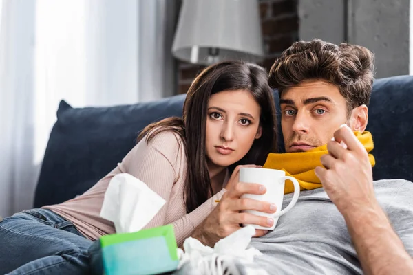 Namorada e namorado doente com xícara de chá olhando para a câmera — Fotografia de Stock
