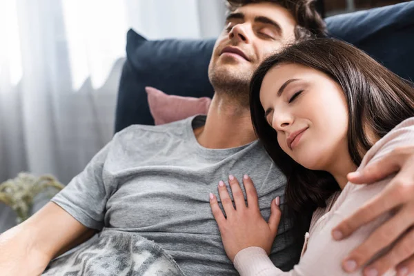 Namorada atraente e namorado bonito com olhos fechados abraçando e deitado na cama — Fotografia de Stock