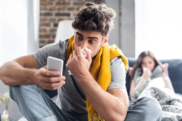 Selective focus of sick boyfriend sneezing and using laptop — Stock Photo