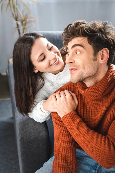 Attractive girlfriend and boyfriend in sweaters smiling and hugging in apartment — Stock Photo