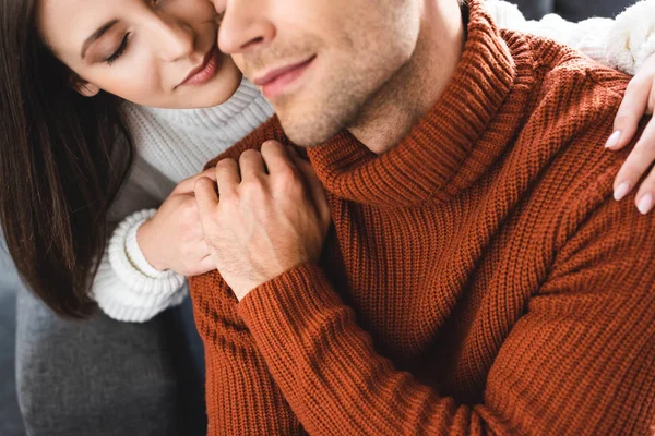 Обрезанный вид на девушку и парня в свитерах, держащихся за руки — стоковое фото