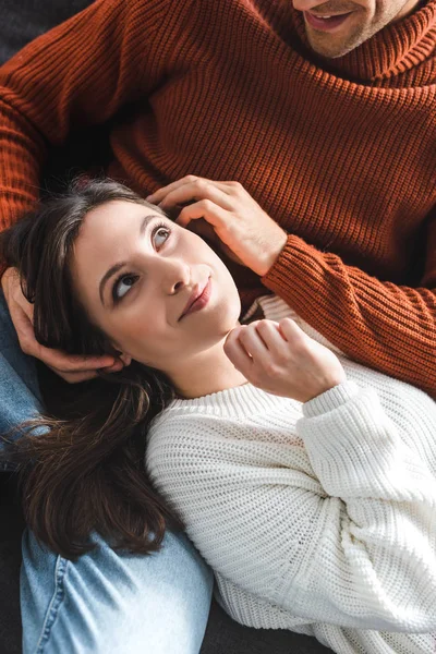 High angle view of attractive girlfriend in sweater smiling and lying on knees of boyfriend — Stock Photo