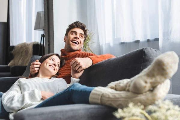 Selective focus of attractive girlfriend in sweater lying on knees of boyfriend — Stock Photo