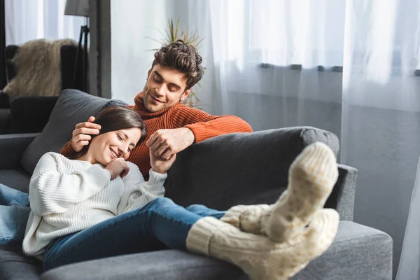 Selective focus of attractive girlfriend in sweater lying on knees of boyfriend — Stock Photo