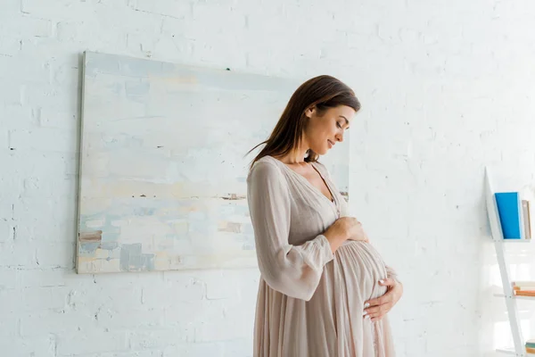 Belle femme enceinte heureuse touchant son ventre à la maison — Photo de stock
