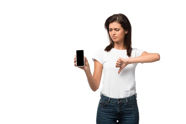 Mujer triste mostrando el pulgar hacia abajo y teléfono inteligente con pantalla en blanco, aislado en blanco - foto de stock