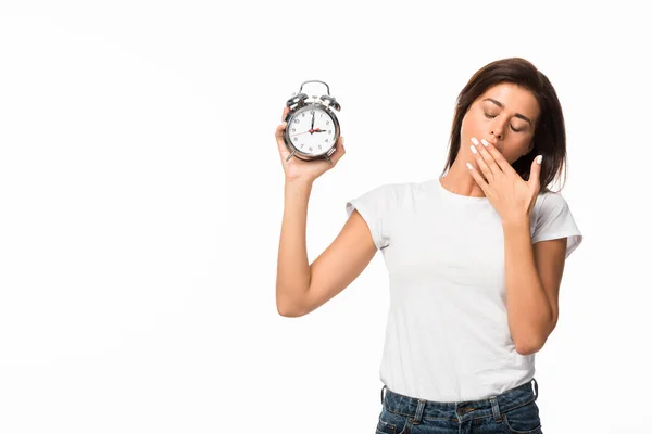 Tired woman yawning and holding alarm clock, isolated on white — Stock Photo