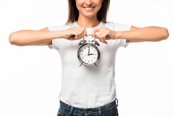 Vista recortada de la mujer sonriente sosteniendo el reloj despertador, aislado en blanco - foto de stock