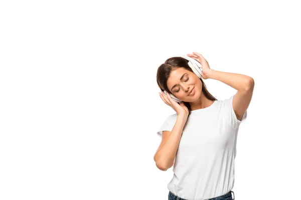 Atractiva mujer con los ojos cerrados escuchando música con auriculares, aislada en blanco - foto de stock