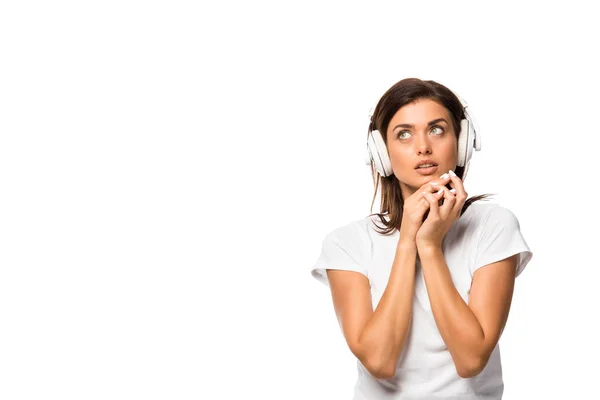 Вдумлива молода жінка слухає музику з навушниками, ізольована на білому — стокове фото