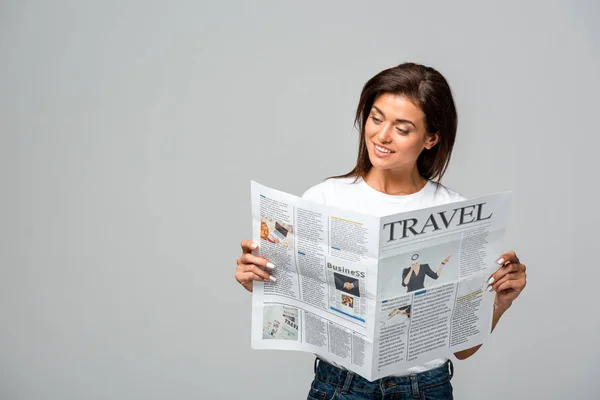Привлекательная улыбающаяся женщина читает туристическую газету, изолированную на сером — стоковое фото