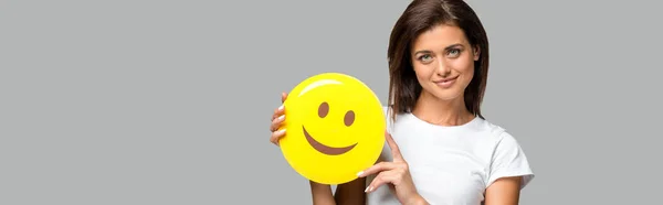QUIIV, UCRÂNIA - SETEMBRO 10, 2019: mulher bonita feliz segurando emoji sorridente amarelo, isolado em cinza — Fotografia de Stock