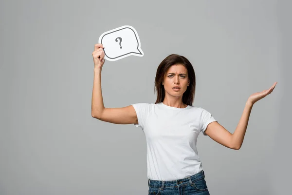 Beautiful worried woman holding speech bubble with question mark, isolated on grey — Stock Photo