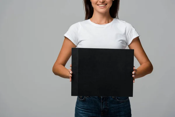 Vista recortada de la mujer sonriente sosteniendo la tarjeta vacía, aislado en gris - foto de stock