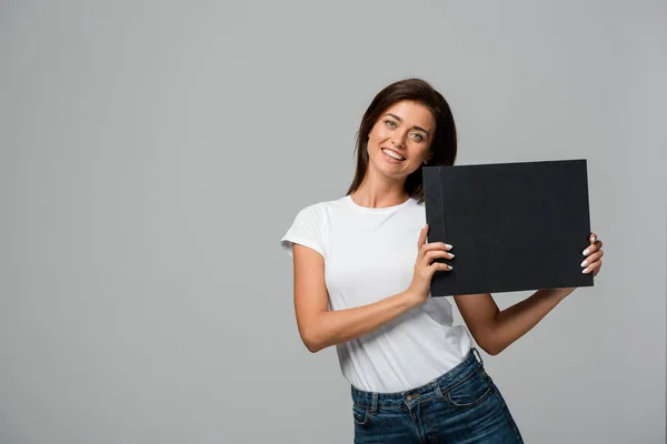 Beautiful happy woman holding empty black board, isolated on grey — Stock Photo