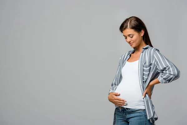 Happy pregnant woman touching belly isolated on grey — Stock Photo