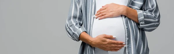 Частичный взгляд беременной женщины, касающейся живота, изолированного на сером — стоковое фото