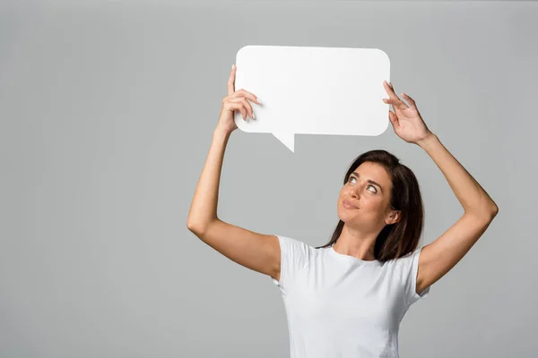 Beautiful smiling woman holding empty speech bubble, isolated on grey — Stock Photo