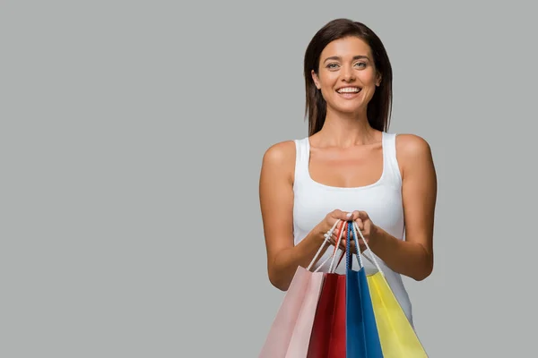 Schöne lächelnde Frau mit Einkaufstaschen, isoliert auf grau — Stockfoto