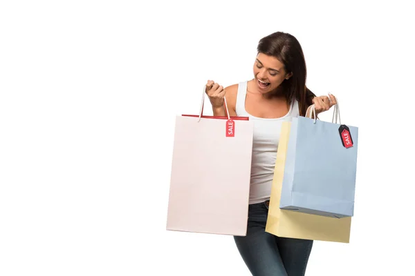 Allegra ragazza che tiene borse della spesa con segni di vendita, isolato su bianco — Foto stock