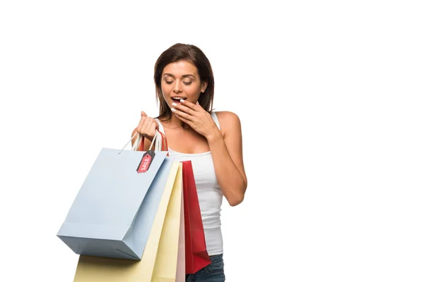 Sorpresa ragazza che tiene borse della spesa con segni di vendita, isolato su bianco — Foto stock