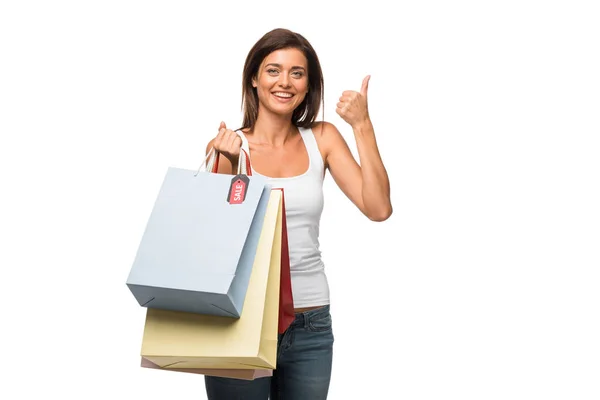 Menina bonita segurando sacos de compras com sinais de venda ao mostrar o polegar para cima, isolado no branco — Fotografia de Stock