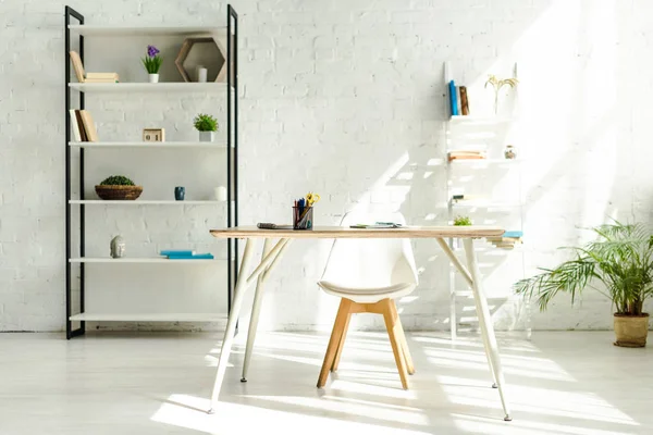 Interior of light modern office with shelves, table and chair — Stock Photo