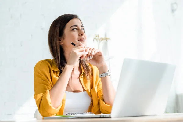 Beautiful thoughtful freelancer working on laptop in home office — Stock Photo