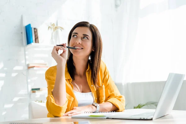 Happy thoughtful freelancer working with notebook and laptop in home office — Stock Photo