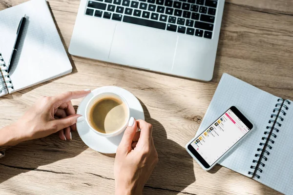 KYIV, UKRAINE - SEPTEMBER 10, 2019: cropped view of freelancer with cup of coffee, laptop and smartphone with apple music app — Stock Photo