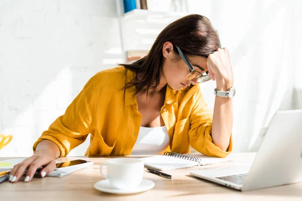 Freelancer cansado trabalhando no laptop com xícara de café no escritório em casa — Fotografia de Stock