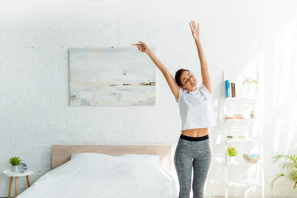 Hermosa chica feliz haciendo ejercicio matutino en el dormitorio - foto de stock