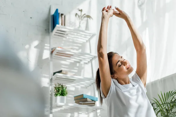 Hermosa mujer estirando los brazos en el dormitorio por la mañana — Stock Photo