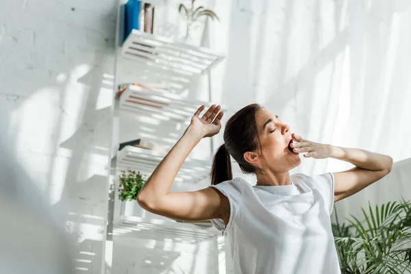 Hermosa mujer bostezando y haciendo ejercicio matutino en el dormitorio - foto de stock