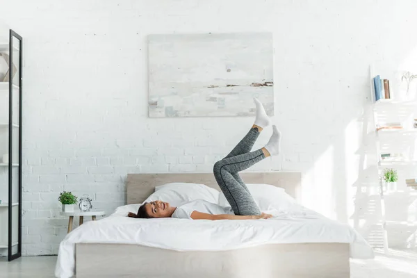 Schönes glückliches Mädchen, das im hellen Schlafzimmer auf dem Bett liegt — Stockfoto