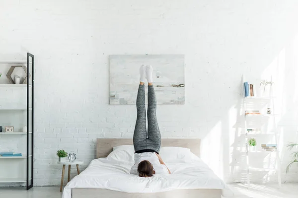 Brunette girl doing morning exercise on bed in bedroom — Stock Photo