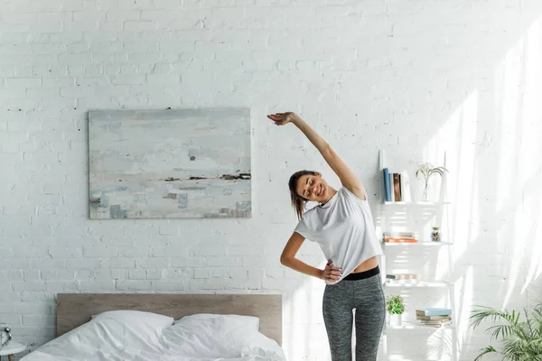 Schöne glückliche Frau macht Morgengymnastik im Schlafzimmer — Stockfoto