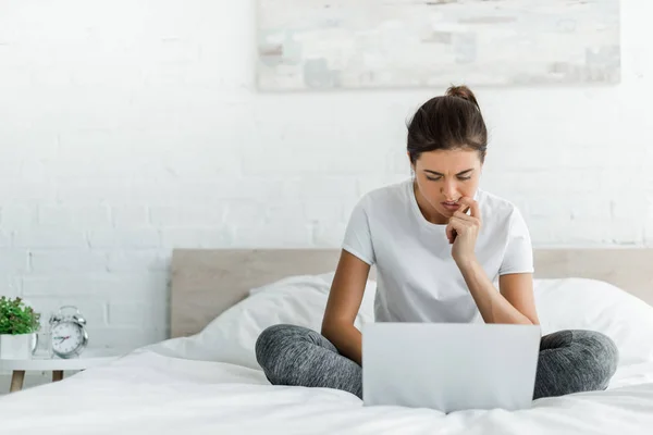 Hermosa chica pensativa usando el ordenador portátil en la cama por la mañana — Stock Photo