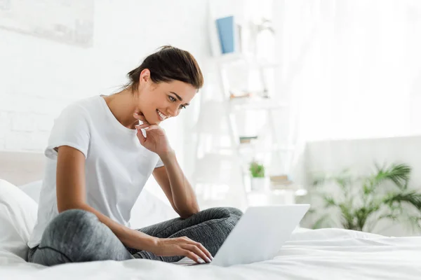 Beautiful happy girl using laptop in bed in the morning — Stock Photo