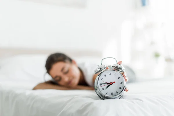 Focalizzazione selettiva della donna addormentata con sveglia sul letto al mattino — Foto stock