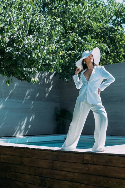Mulher atraente em terno branco e chapéu posando fora — Fotografia de Stock