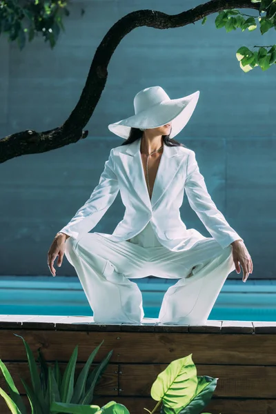 Femme adulte en costume blanc et chapeau posant à l'extérieur — Photo de stock
