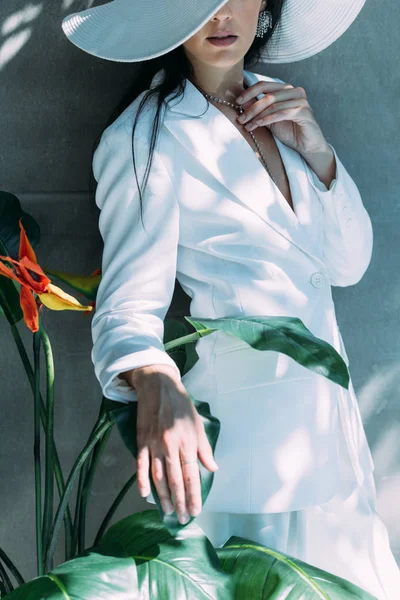 Обрізаний вид жінки в білому костюмі і капелюсі позує зовні — стокове фото